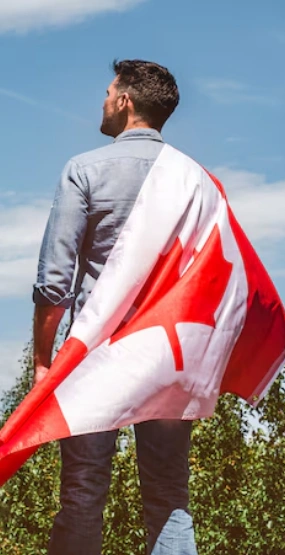 A man in the forest holding a Canadian flag.